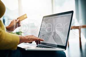 Treat yourself to the convenience of online shopping. Cropped shot of a woman using her credit card to make an online payment at home.