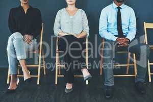 It all about the way you carry yourself. Cropped of a group of well-dressed business people seated in line while waiting to be interview.