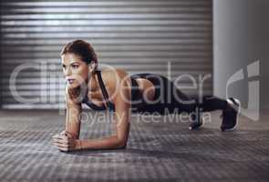 Working her core muscles to the max with some planks. Shot of a young woman doing a plank exercise at the gym.