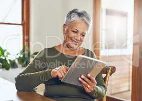 She gets all her news online. Shot of a mature woman using a digital tablet at home.