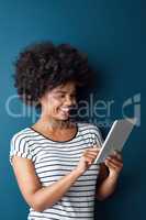 Diving right in to the digital world. Studio shot of an attractive young woman using a digital tablet against a blue background.