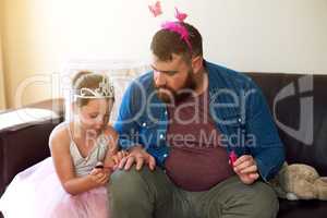 Putting the man in manicure. Shot of an adorable little girl painting her fathers nails at home.