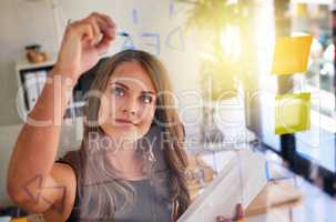 Shes brimming with bright ideas. Shot of an inspired young businesswoman laying out a business plan with adhesive notes against a glass wall.