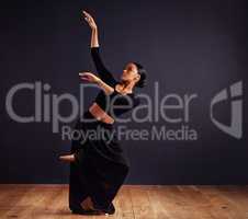 Mysteries of the dance. Female contemporary dancer in a dramatic pose against dark background.