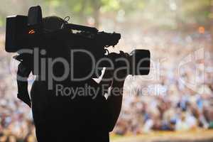 Capturing the excitement. A silhouette of a cameraman filming an event.