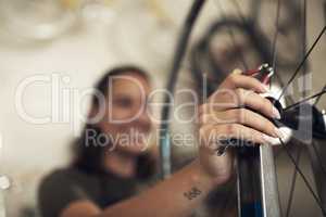 Say goodbye to bike problems. Shot of an unrecognizable woman standing alone in her shop and repairing a bicycle wheel.