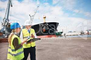 Open communication brings results. Two dock workers holding paperwork while standing in the shipyard.