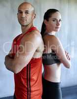 They're in peak physical condition. Portrait of a young couple in gym wear standing back to back.