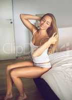 Morningsbeautiful beginnings. Shot of an attractive young woman relaxing in her bedroom in the morning.