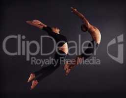 Freedom of flight. A female and male contemporary dancer performing a dramatic pose in front of a dark background.