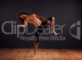 Free form expression. Male contemporary dancer performing a dramatic pose in front of a dark background.