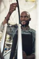 Making sure its aligned. Shot of a handsome young man standing alone in his shop and repairing a bicycle wheel.