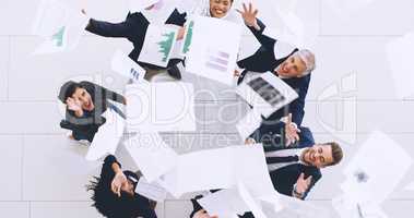 Were done for the day. Aerial shot of a diverse group of businesspeople throwing paperwork in the air in celebration while in the office.