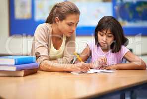 She's a dedicated educator. Shot of a teacher helping her student with her work in the classroom.