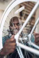 Oh DIdnt see you there. Shot of a handsome young man crouching in his shop and repairing a bicycle wheel.