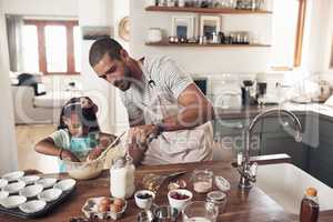 Bake someone happy. Shot of a father teaching his daughter how to bake in the kitchen at home.