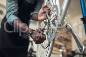We dont want this falling off. Shot of an unrecognizable man standing alone in his shop and repairing a bicycle wheel.
