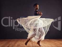 Poetry in motion. Young female contemporary dancer using a soft white white skirt for dramatic effect.