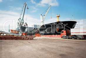 Importing and exporting never ceases. A photo of a harbor with anchored ships and a stationary truck.