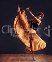 Dedication to expression. Female contemporary dancer in a dramatic pose against dark background.