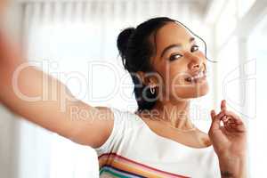 Staying relevant with my followers. Cropped portrait of an attractive young blogger standing in her home and making a peace sign gesture for a selfie.