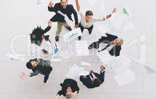 This is what freedom looks like. Aerial shot of a diverse group of businesspeople throwing paperwork in the air in celebration while in the office.