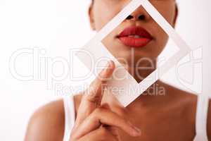 Red lipstick speaks volumes. Studio shot of an unrecognizable woman holding a frame over her red lips.