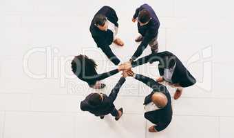 Teamwork turns the wheels of a business. High angle shot of a group of businesspeople joining their hands in solidarity.