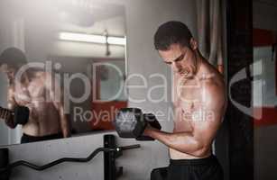 Focusing on his biceps. Cropped shot of a handsome and muscular young man working out with a dumbbell in the gym.