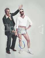 Agent pushing his new tallent. A mature man in a retro suit trying to present a young man in retro tennis clothes.
