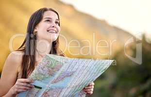 Theres so many beautiful sights here. Shot of a young woman holding a map while out exploring.