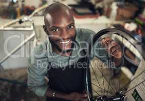 Adding that magical touch. High angle shot of a handsome young man standing alone in his shop and repairing a bicycle wheel.