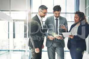 Putting together a plan. Shot of a group of coworkers talking together over a digital tablet in an office.