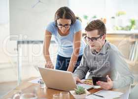 Immersed in the designing process. Shot of two designers working together on a laptop in an office.