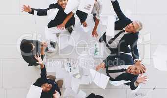 Aerial shot of a diverse group of businesspeople throwing paperwork in the air in celebration while in the office