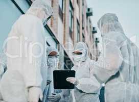 Teamwork makes infection control work. Shot of a group of healthcare workers wearing hazmat suits working together during an outbreak in the city.