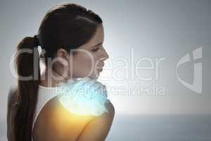 Trying to stop the swelling. Shot of a young woman holding an icepack on her shoulder to ease the pain.