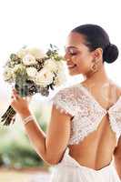 Happy brides turn into happy wives. Shot of a beautiful young bride holding a bouquet of flowers outdoors on her wedding day.