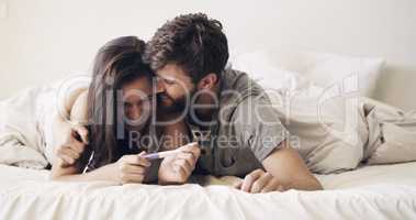 We're going to make great parents. Shot of a happy young couple taking a pregnancy test at home.