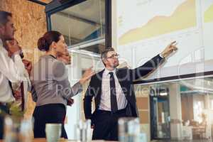 Running through the numbers with his team. Shot of an executive giving a presentation on a projection screen to a group of colleagues in a boardroom.