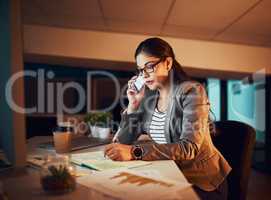 Late night calls. Shot of a young businesswoman working late in the office.