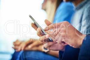 Modern technology is the new trend. Cropped shot of unrecognizable businessman using a smartphone during a conference in a modern office.