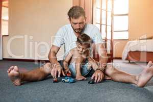 The ultimate father son bonding activity, playing with cars. Shot of a little boy and his father playing with toy cars at home.