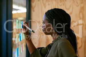 Laying out her ideas. Cropped shot of a young designer writing her ideas on adhesive notes.