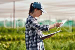 These numbers look promising. Cropped shot of an attractive young female farmer looking over paperwork while working on her farm.