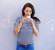 Now that's a fine brew. Portrait of a an attractive woman holding a coffee cup against a gray background.