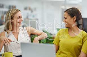 Office jokes are the best. Two attractive females laughing at their desk in the office.