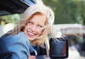 Feeling breezy. A young woman feeling the breeze in her hair through an open car window.