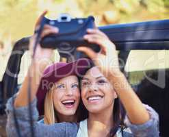Picture perfect moments. Shot of a two girlfriends taking self-portraits while on a roadtrip.