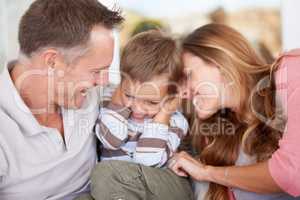 Beware the tickle monster. Shot of parents tickling their young son.